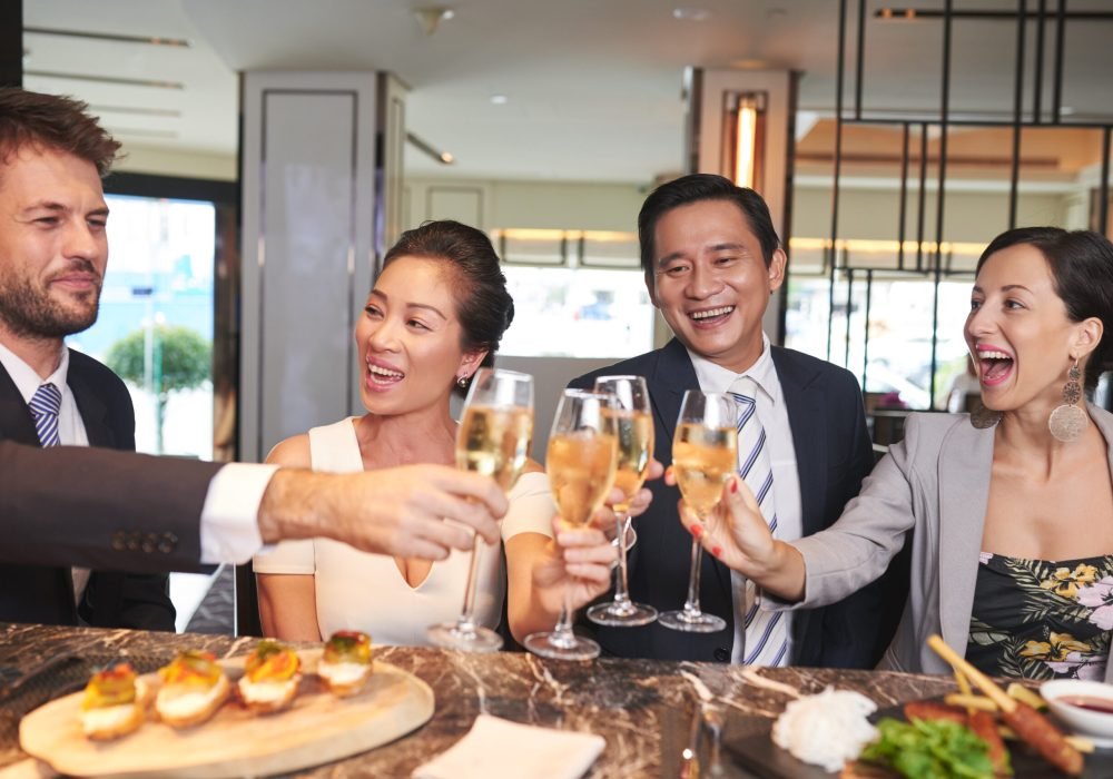 Cheerful friends drinking champagne at dinner in restaurant
